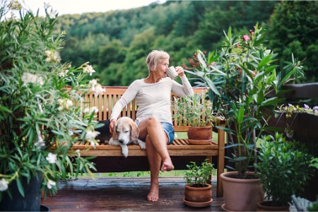 retired woman drinking coffee outdoors with dog